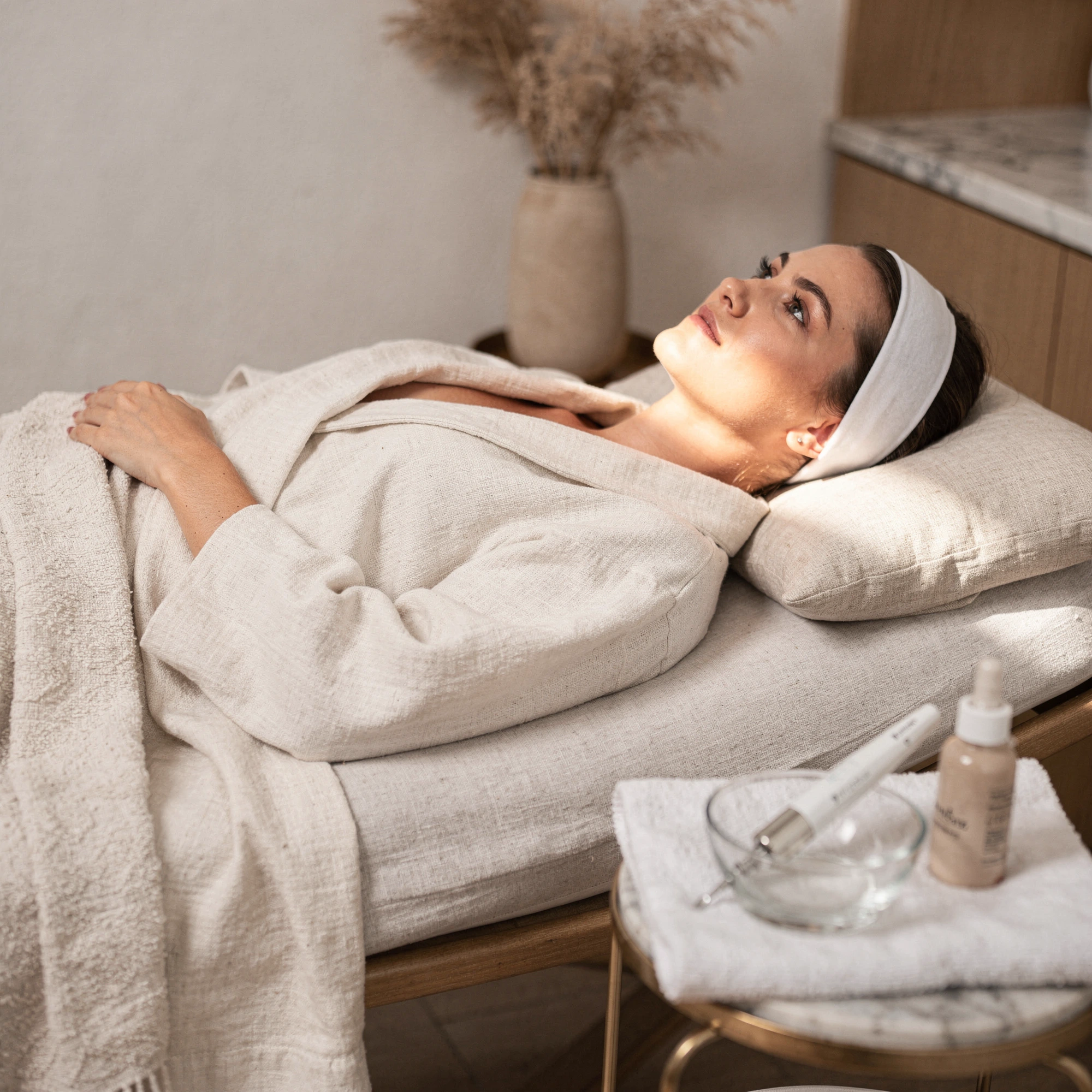 Patient relaxing on treatment bed with headband, treatment products on nearby table